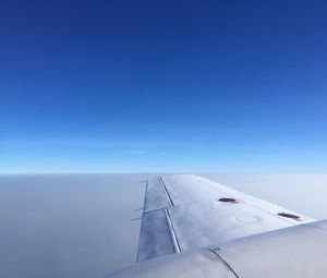 Airplane flying over sea against clear blue sky