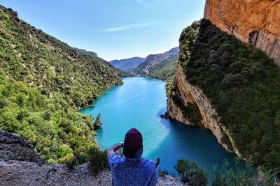 Rear view of man looking at river against mountains