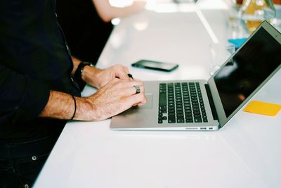 Close-up of man using laptop on table