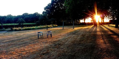 Empty bench in park against sky