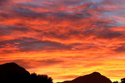 Low angle view of silhouette mountains against orange sky