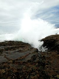 Waves splashing on shore against sky