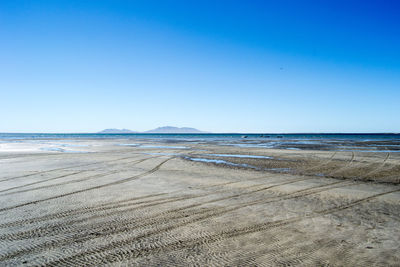 Scenic view of beach against clear blue sky