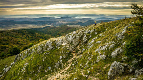 Young woman hiking on mountain against cloudy sky during sunset