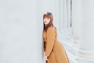 Portrait of woman leaning on column