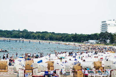 Crowd and hooded chairs at beach against clear sky