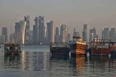 Boats in sea by buildings against sky in city