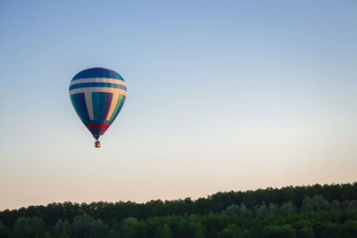 Low angle view of hot air balloons against clear sky over trees