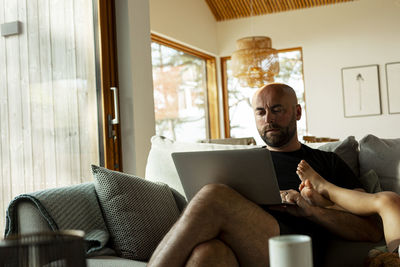 Mature man using laptop while working from home in living room