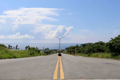 Road by trees against sky