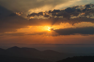 Scenic view of silhouette mountains against orange sky