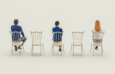 Rear view of people sitting on chair against white background