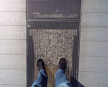 Low section of man standing on metal grate