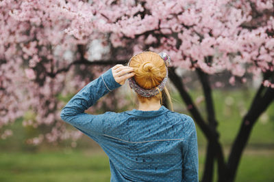 Back view of redhead woman standing in front of cherry blossom tree