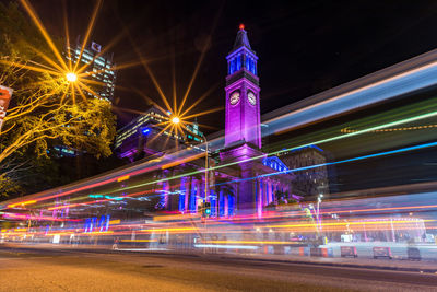 Light trails on road against buildings at night