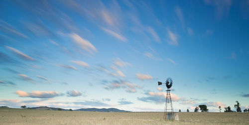 Windmill on grass field against sky