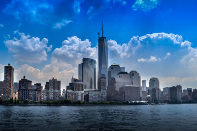 City at waterfront against cloudy sky