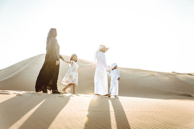 Arabian family standing at desert against sky