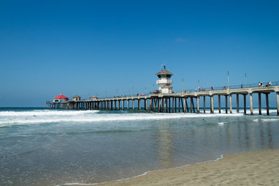 Pier over sea against clear blue sky