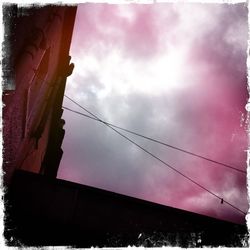Low angle view of power lines against cloudy sky