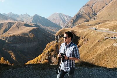 Young man standing on mountain against mountains