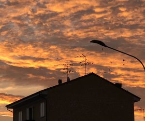 Low angle view of silhouette buildings against orange sky