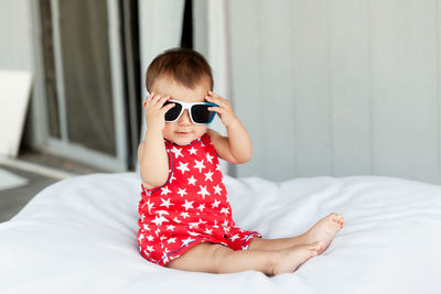 Portrait of cute girl sitting on bed at home