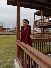 Portrait of smiling young woman standing against railing