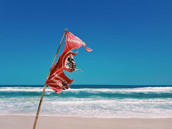 Lifeguard hut in sea against clear blue sky