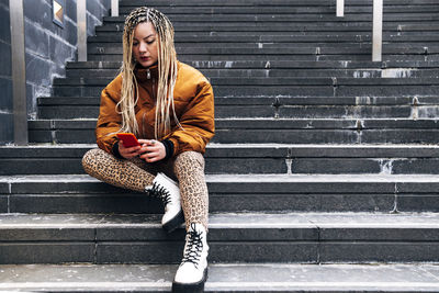 Full length of woman sitting on staircase