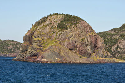 Rock formation in sea against clear sky