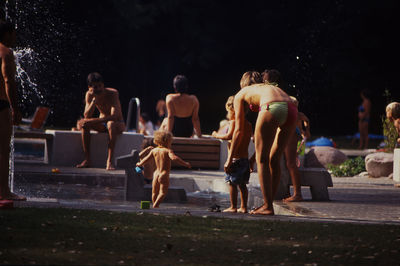 Rear view of people sitting in park at night