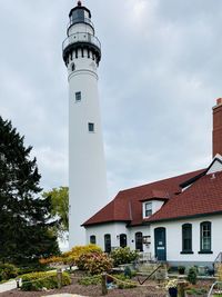 Low angle view of lighthouse by building against sky