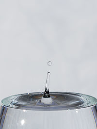 Close-up of drop falling on water against white background