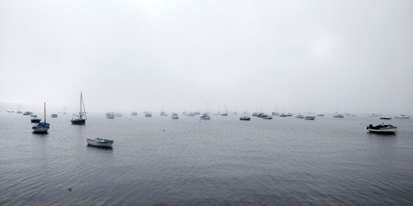 Sailboats in sea against sky