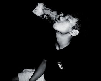 Midsection of man smoking against black background