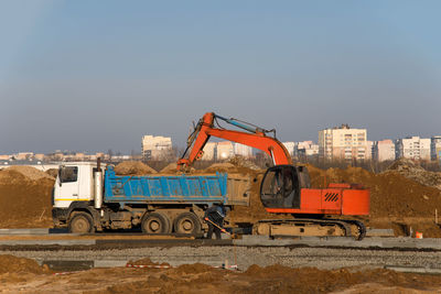 Construction site by road against sky in city