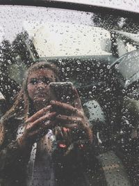 Reflection of man photographing on wet glass