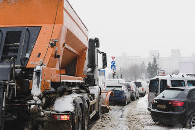 Cars on snow covered city against clear sky