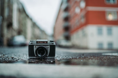 Close-up of vintage camera against building in city