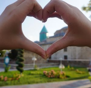 Cropped hands of woman making heart shape