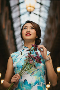 Low angle view of woman holding flowers