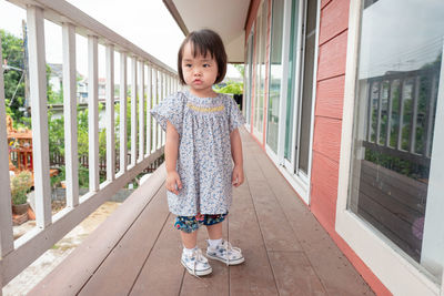 Full length of cute baby girl looking away while standing in balcony