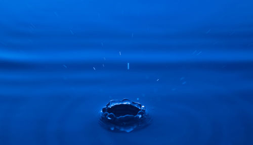 Close-up of drop falling on blue water