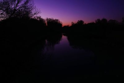 Reflection of silhouette trees in lake against sky at sunset