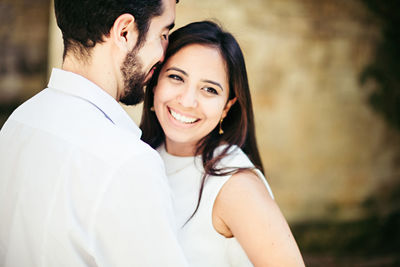 Happy couple romancing while standing against wall