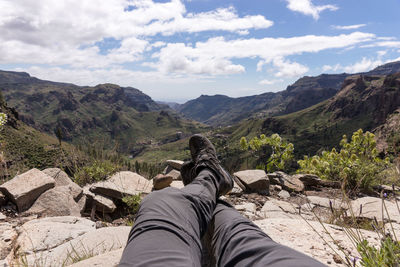 Low section of person on mountain against sky