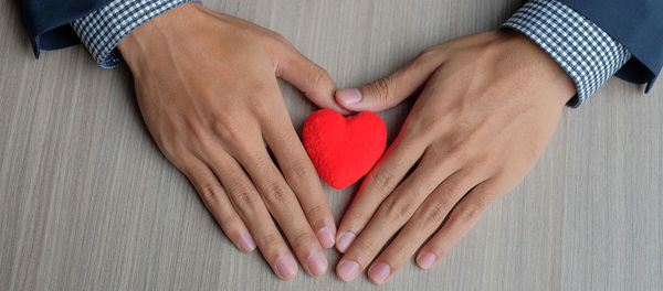 Midsection of woman holding heart shape with hands