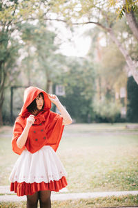 Young woman wearing red hood while standing in public park