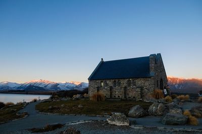 House by lake against clear blue sky